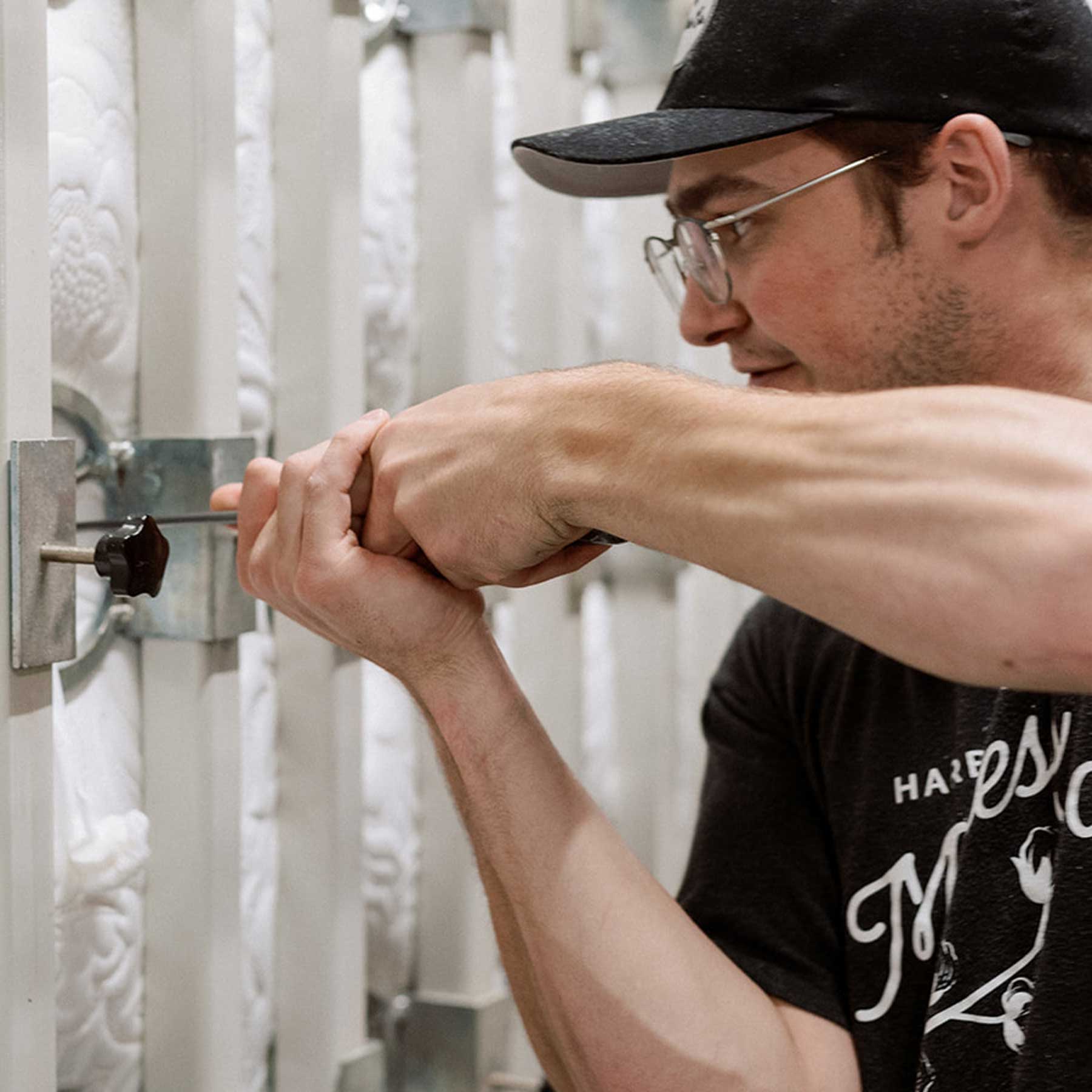 Man hand-tufting a natural and organic luxury mattress in the workshop of Harbor Springs Mattress Co..