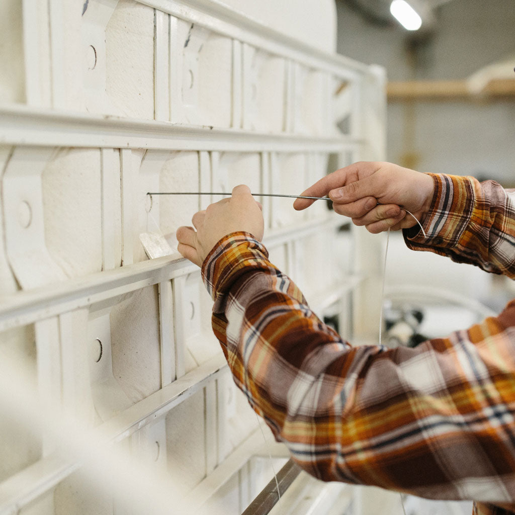 Craftsman hand-tufting a luxury natural mattress at the mattress workshop of Harbor Springs Mattress Co.