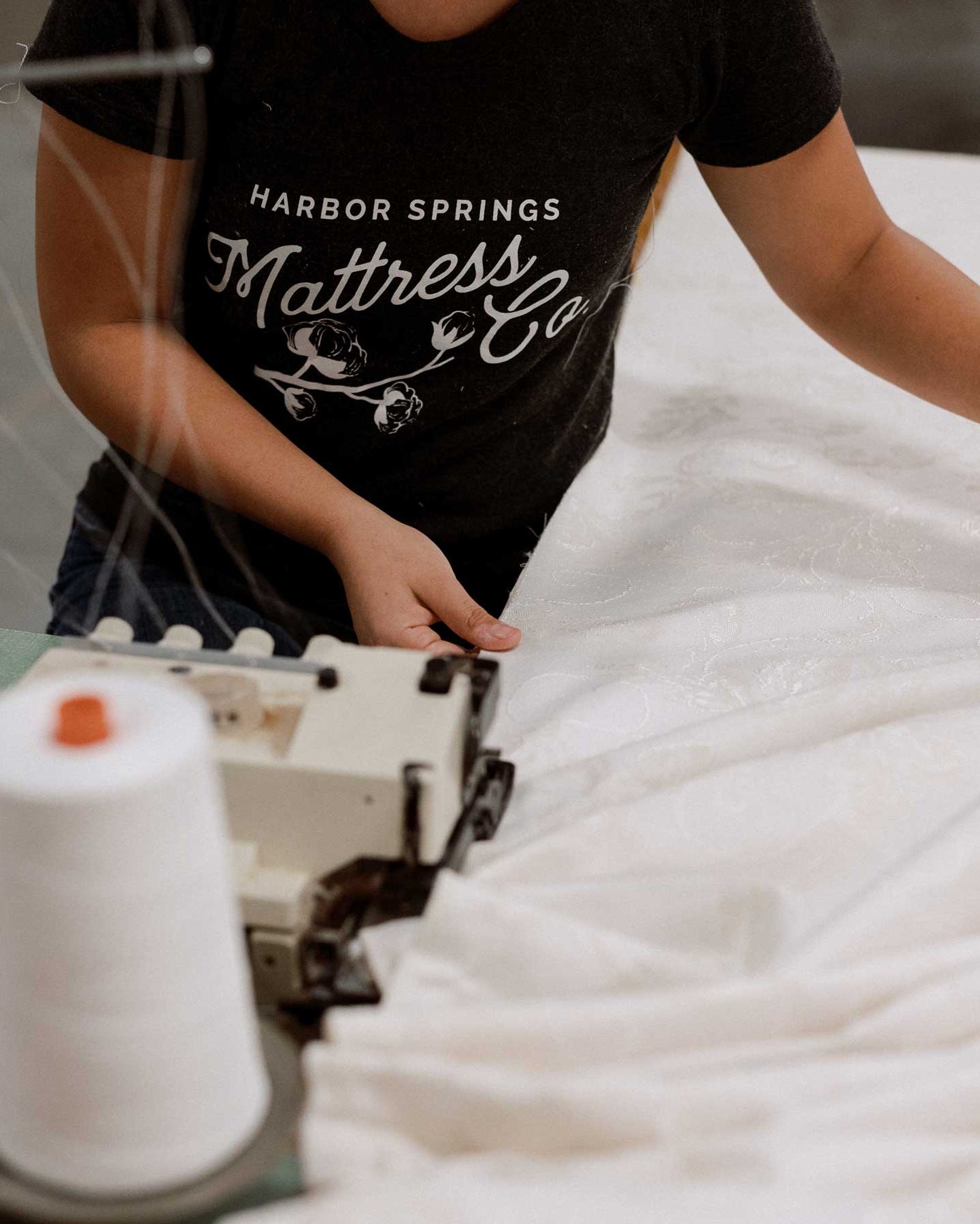 woman sewing luxury white mattress ticking fabric at mattress manufacturing factory in Harbor Springs, Michigan.