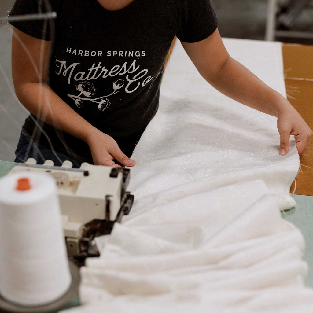 woman sewing luxury white mattress ticking fabric at mattress manufacturing factory in Harbor Springs, Michigan.