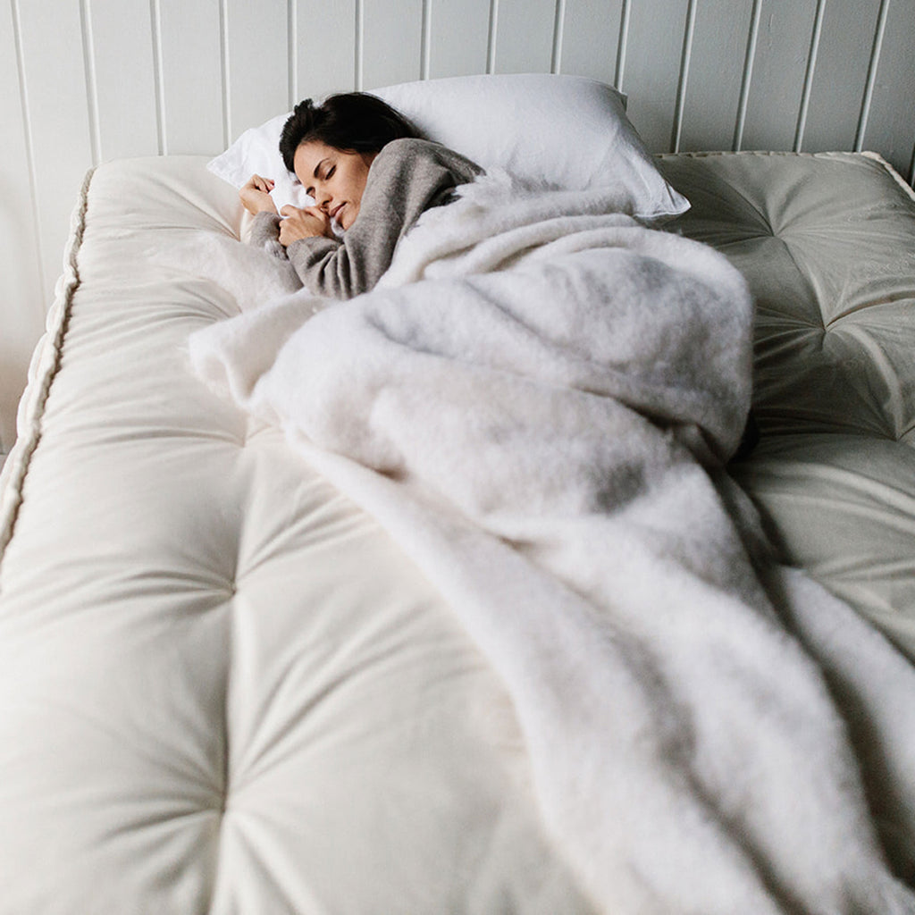 woman sleeping with a soft blanket on a luxury mattress made with natural and organic fibers.