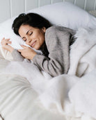 women sleeping on a Trillium Mattress fromm Harbor Springs Mattress with cozy blanket and a soft smile on her face.