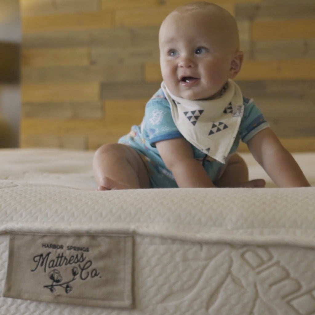 Baby smiling on luxury natural latex mattress called the cozy.