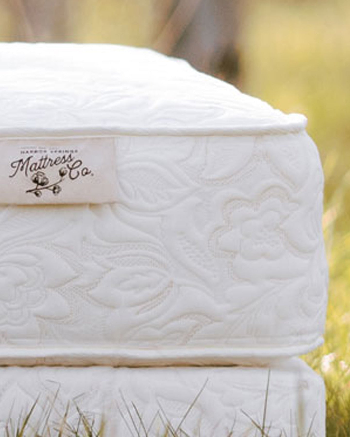 picture of a harbor springs mattress bed in  the grass with the cotton flower logo showing.