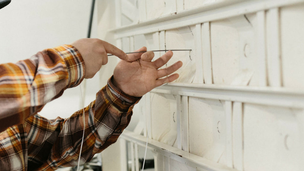 Craftsman hand tufting a luxury innerspring mattress in the tufting press at Harbor Springs Mattress Co.