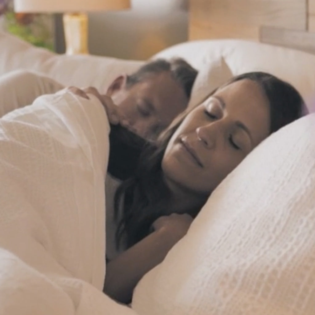Couple sleeping in a harbor springs mattress bed while filming for a testimonial.