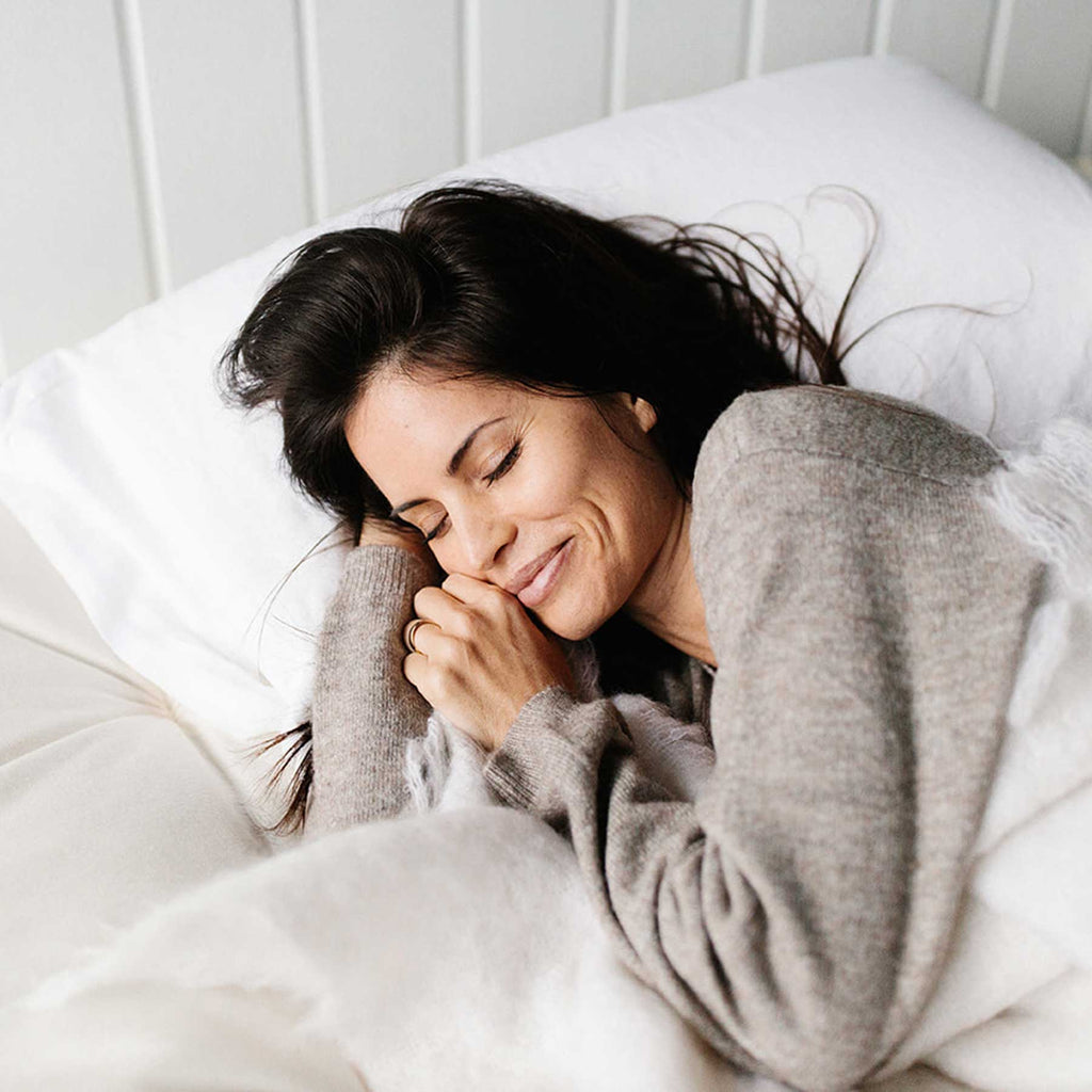 Woman smiling while asleep on a hand-tufted all-natural luxury mattress.