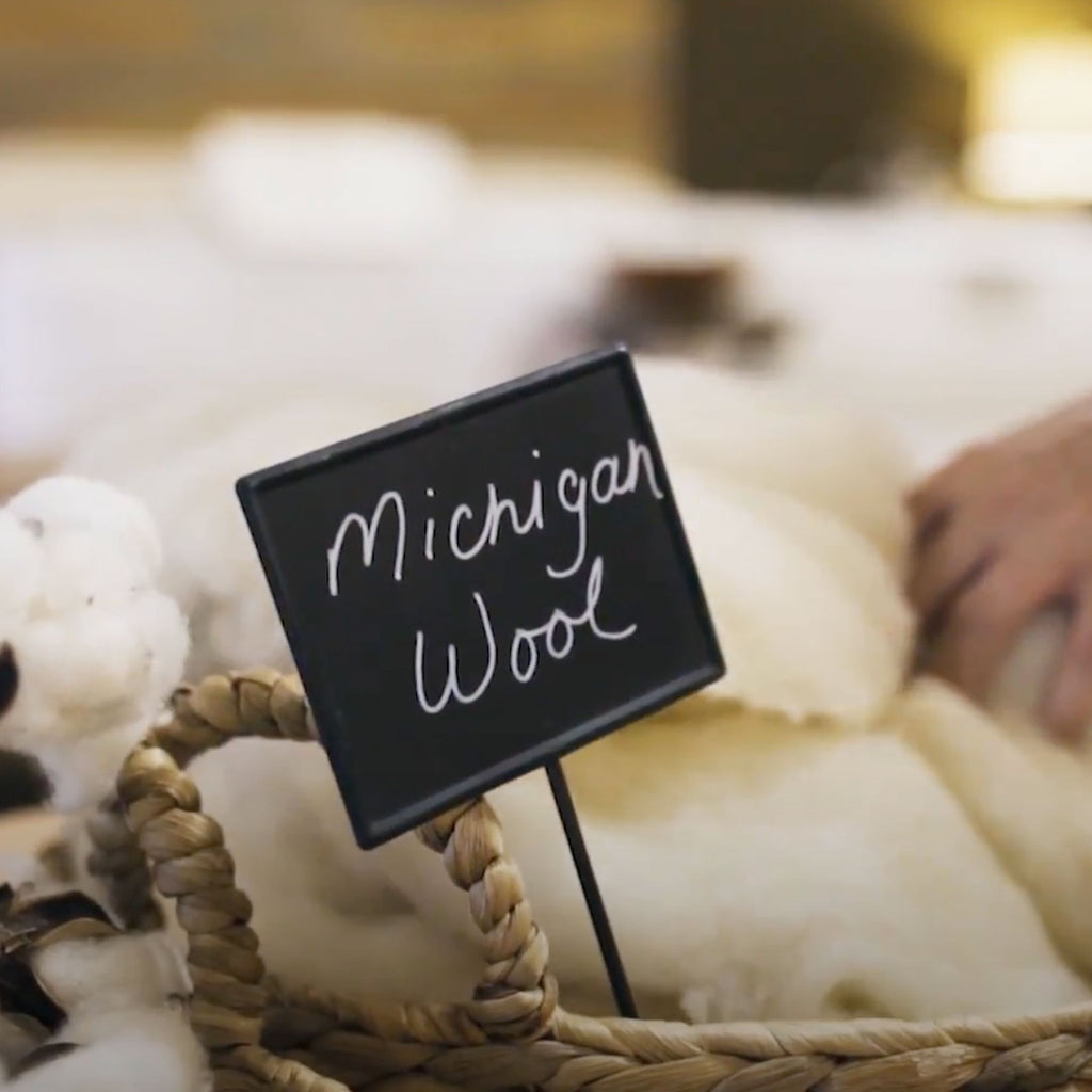 Close up of sign that says Michigan Wool in a basket of wool used in organic mattress making.