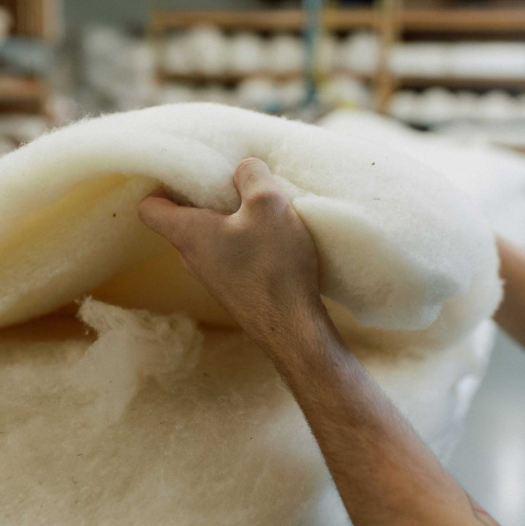 Hand layering organic wool over innersprings for a luxury mattress being made in Michigan.